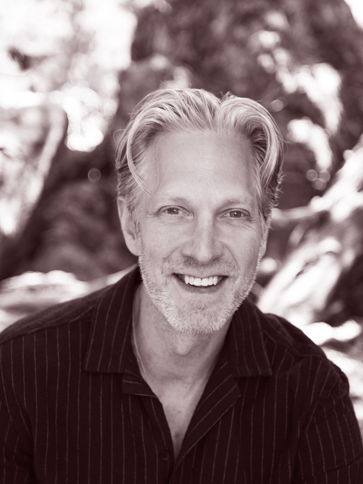 Randy smiling outdoors in a striped shirt