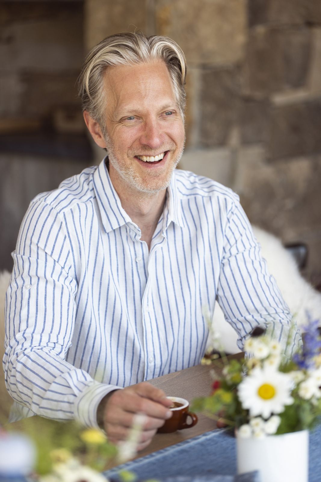 Randy smiling at a table with coffee and flowers