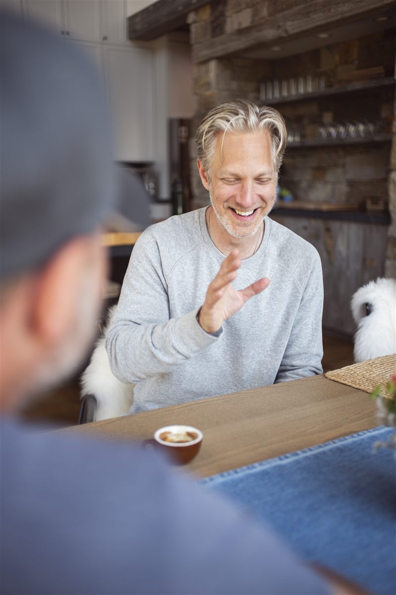 Randy smiling during a conversation with another person in the foreground